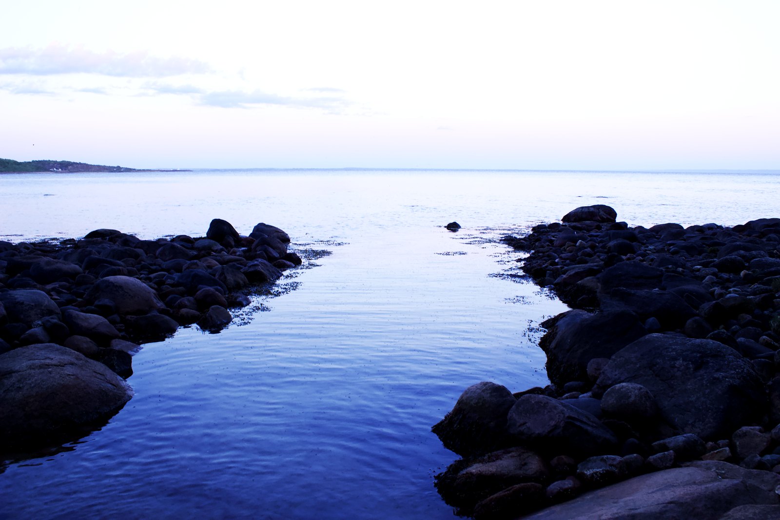 Stenpir ut i havet i blå timmen